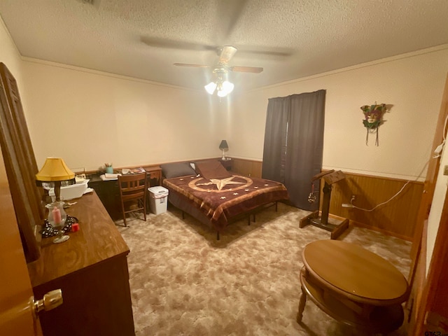 carpeted bedroom with wood walls, ceiling fan, a textured ceiling, and crown molding