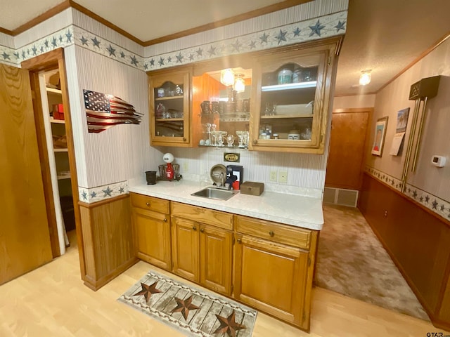 kitchen featuring sink, light hardwood / wood-style flooring, and crown molding