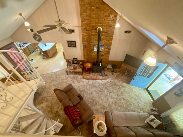 interior space featuring a wood stove, high vaulted ceiling, hardwood / wood-style flooring, and ceiling fan