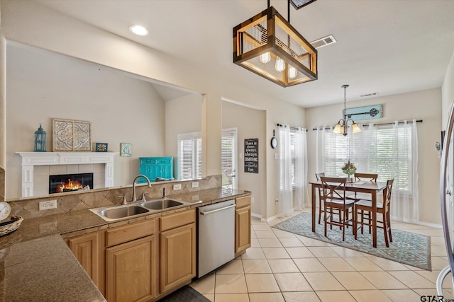 kitchen featuring dishwasher, a tiled fireplace, sink, decorative light fixtures, and a chandelier