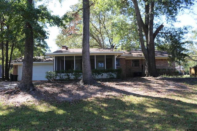 exterior space featuring a front yard, a garage, and a sunroom