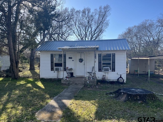 bungalow featuring a front yard, metal roof, cooling unit, and fence