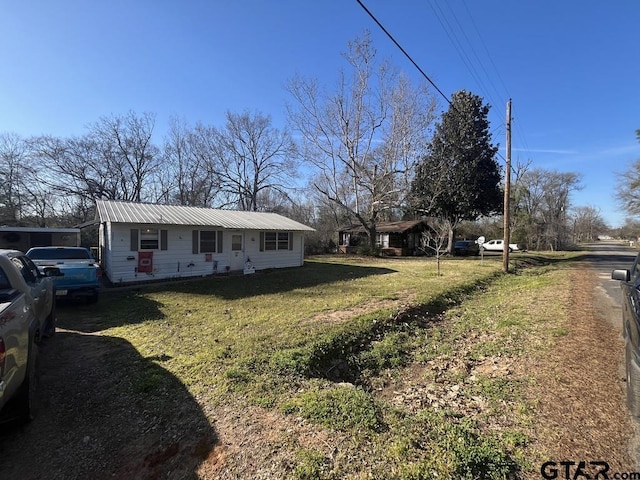 view of front of property with metal roof and a front lawn