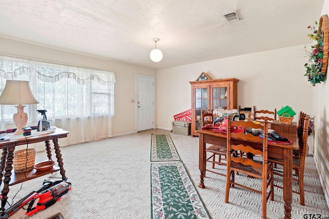 carpeted dining room with a textured ceiling