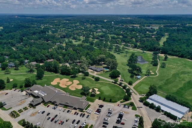 drone / aerial view featuring golf course view and a view of trees