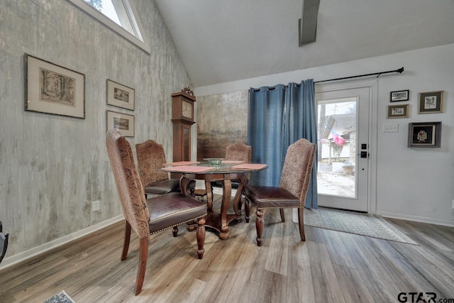 dining space with wood finished floors, baseboards, and high vaulted ceiling