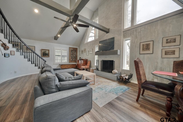 living area featuring stairway, a fireplace, baseboards, and wood finished floors