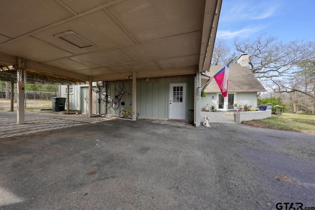 exterior space featuring a carport, fence, and a chimney