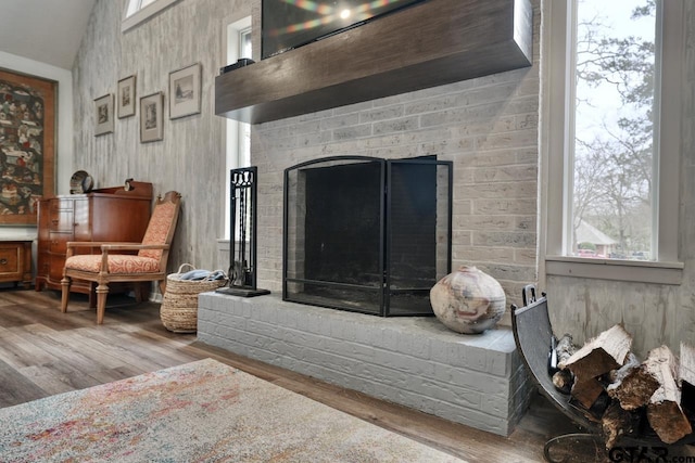 interior space with a brick fireplace and wood finished floors