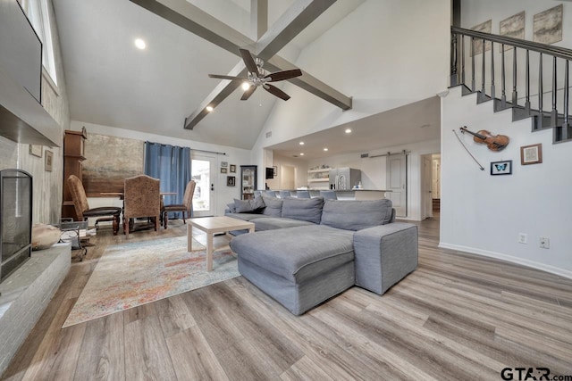 living area featuring a barn door, baseboards, high vaulted ceiling, and wood finished floors