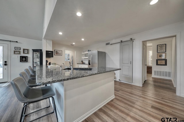 kitchen featuring a barn door, light wood-style floors, stainless steel fridge, and a sink