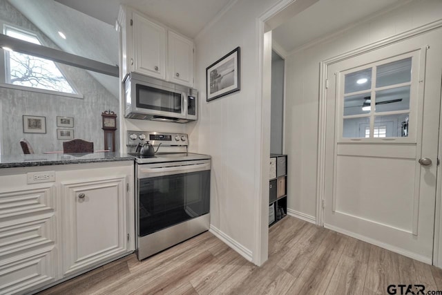 kitchen featuring light wood-style flooring, appliances with stainless steel finishes, white cabinetry, and dark stone countertops