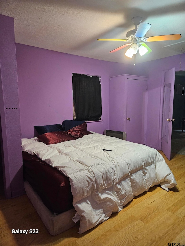 bedroom featuring wood-type flooring, ceiling fan, and a textured ceiling