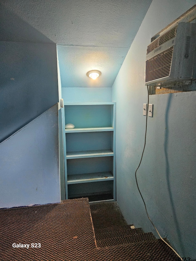 basement featuring a wall unit AC and a textured ceiling