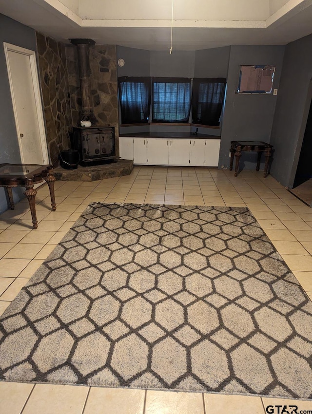 unfurnished living room featuring a wood stove and light tile patterned flooring