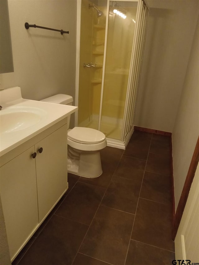 bathroom featuring toilet, vanity, tile patterned floors, and a shower with shower door