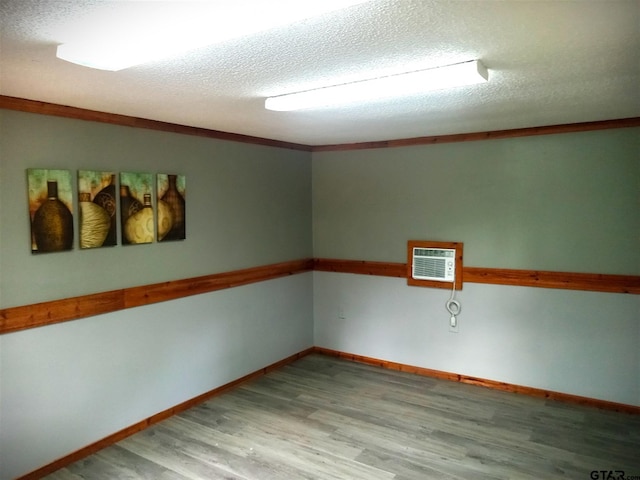 unfurnished room featuring a wall mounted AC, light hardwood / wood-style flooring, and a textured ceiling