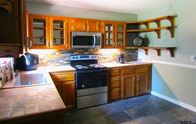 kitchen featuring stainless steel appliances, tile counters, sink, and tasteful backsplash