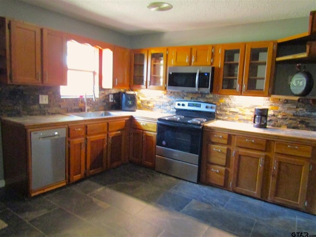 kitchen featuring decorative backsplash, appliances with stainless steel finishes, sink, and dark tile patterned flooring