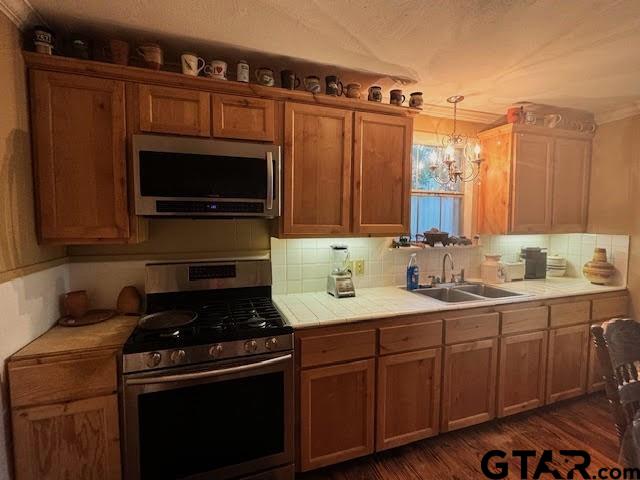 kitchen with sink, hanging light fixtures, stainless steel appliances, dark hardwood / wood-style floors, and a chandelier