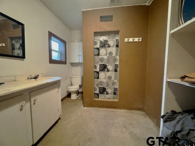 bathroom featuring curtained shower, vanity, concrete floors, and toilet