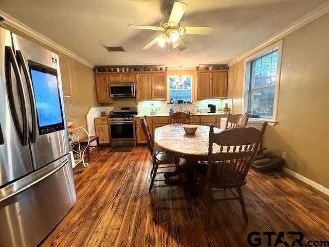 kitchen with a wealth of natural light, dark hardwood / wood-style flooring, ornamental molding, and appliances with stainless steel finishes