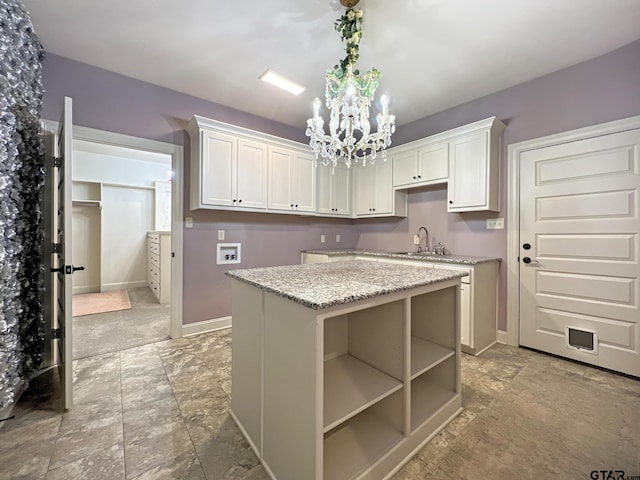 kitchen with pendant lighting, white cabinetry, a center island, a notable chandelier, and light stone counters