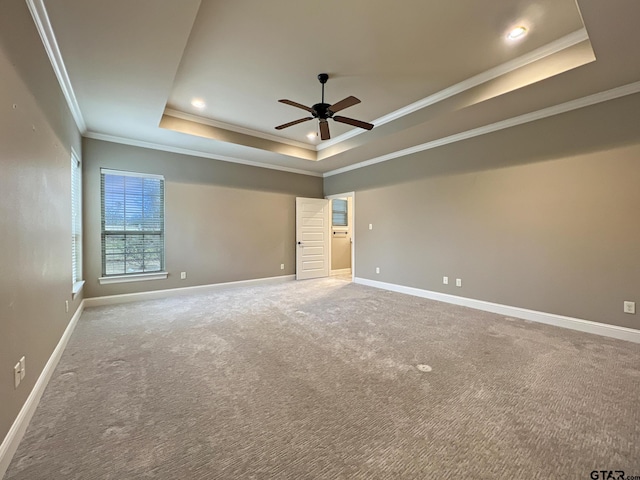 empty room featuring ornamental molding, carpet floors, ceiling fan, and a tray ceiling