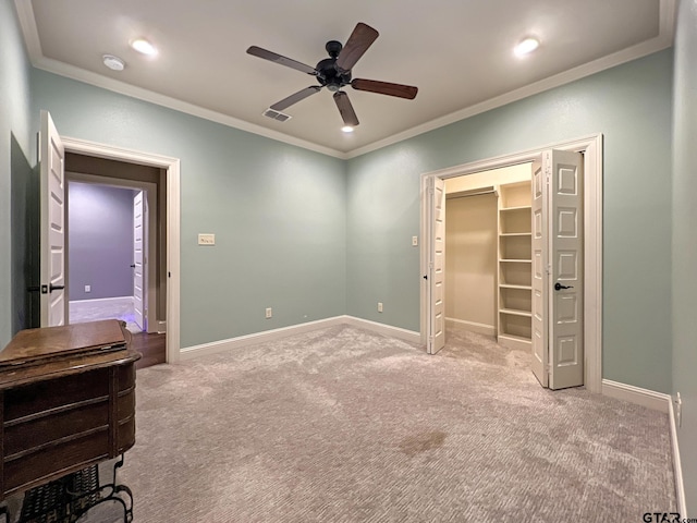 carpeted bedroom featuring ceiling fan, a walk in closet, and ornamental molding