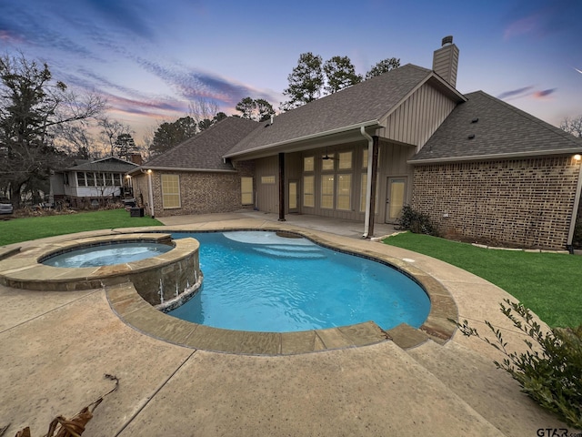 pool at dusk featuring an in ground hot tub, a yard, and a patio area