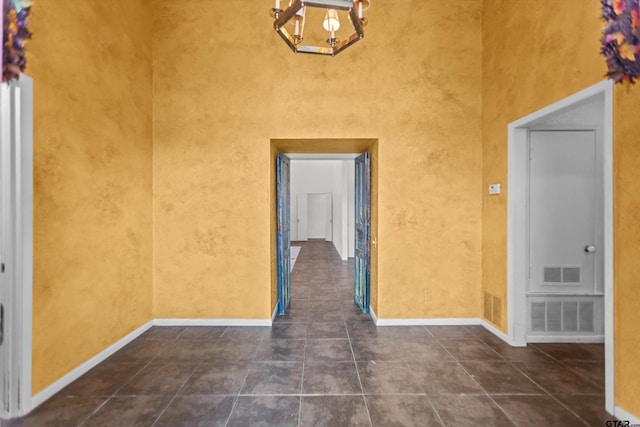 corridor featuring tile patterned flooring, visible vents, and a notable chandelier