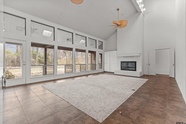 unfurnished living room with ceiling fan, a fireplace, high vaulted ceiling, and tile patterned floors