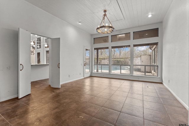 interior space with a chandelier, a towering ceiling, baseboards, and tile patterned floors