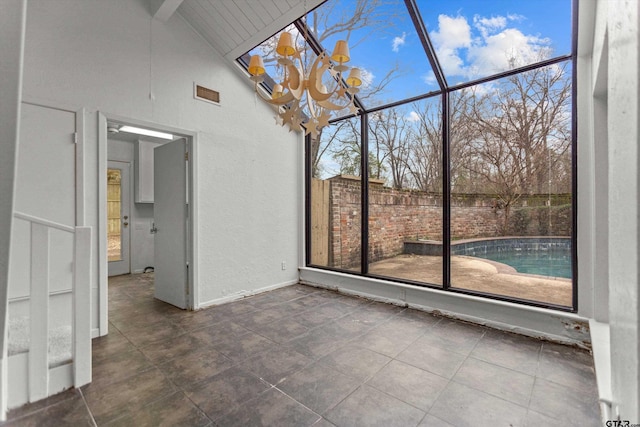 unfurnished sunroom featuring lofted ceiling with beams