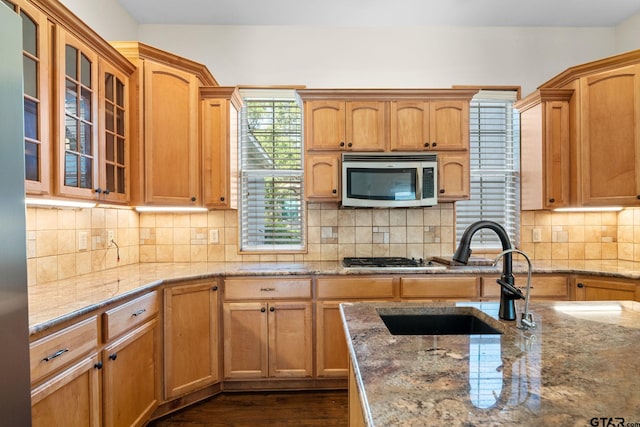 7031 Ridge Place Cir, Tyler, TX 75703 - kitchen with appliances with stainless steel finishes, light stone counters, glass insert cabinets, tasteful backsplash, and dark wood-style flooring