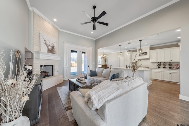 living room with a brick fireplace, dark hardwood / wood-style flooring, ceiling fan with notable chandelier, and ornamental molding