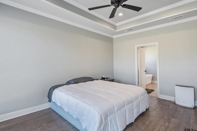 bedroom with ceiling fan, dark hardwood / wood-style floors, ensuite bath, a raised ceiling, and crown molding