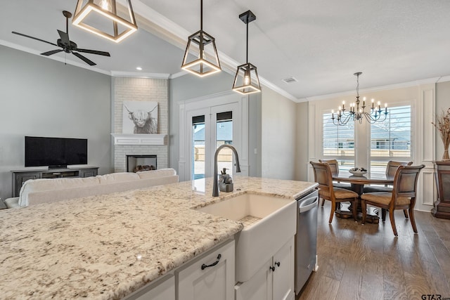 kitchen featuring white cabinetry, ceiling fan with notable chandelier, a fireplace, pendant lighting, and stainless steel dishwasher