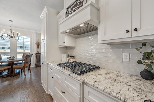 kitchen featuring tasteful backsplash, custom exhaust hood, crown molding, stainless steel gas cooktop, and white cabinets