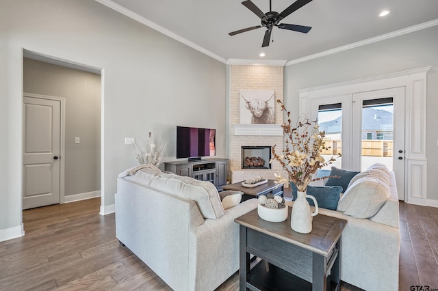 living room with ceiling fan, wood-type flooring, a fireplace, and ornamental molding