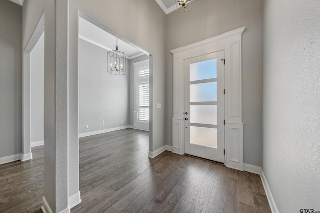 foyer entrance with dark hardwood / wood-style floors, crown molding, and a notable chandelier