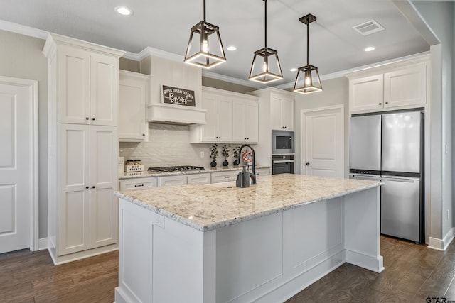 kitchen featuring stainless steel appliances, an island with sink, white cabinets, and decorative light fixtures