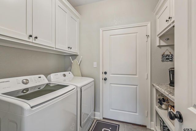 clothes washing area featuring washing machine and dryer, cabinets, and light tile patterned floors