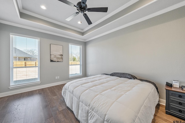 bedroom with ceiling fan, dark wood-type flooring, crown molding, and a raised ceiling