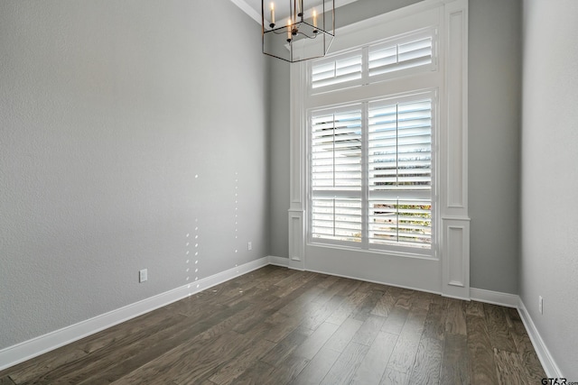 empty room featuring dark wood-type flooring and a notable chandelier