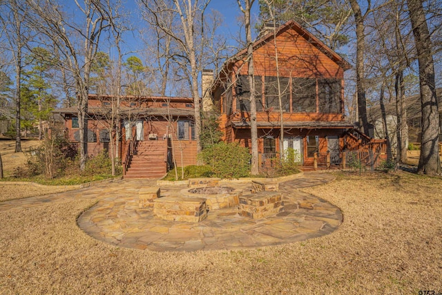 chalet / cabin featuring an outdoor fire pit, a patio, a sunroom, a chimney, and stairs