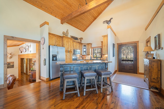 kitchen featuring dark wood-type flooring, a kitchen breakfast bar, appliances with stainless steel finishes, beam ceiling, and glass insert cabinets