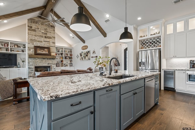 kitchen featuring sink, decorative light fixtures, appliances with stainless steel finishes, a kitchen island with sink, and white cabinets