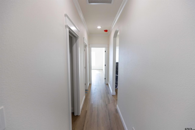 hall with light hardwood / wood-style floors and crown molding