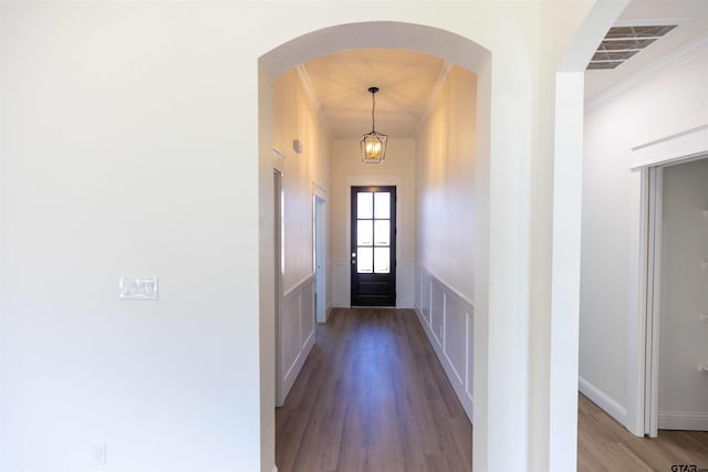 entryway with hardwood / wood-style flooring, crown molding, and a notable chandelier